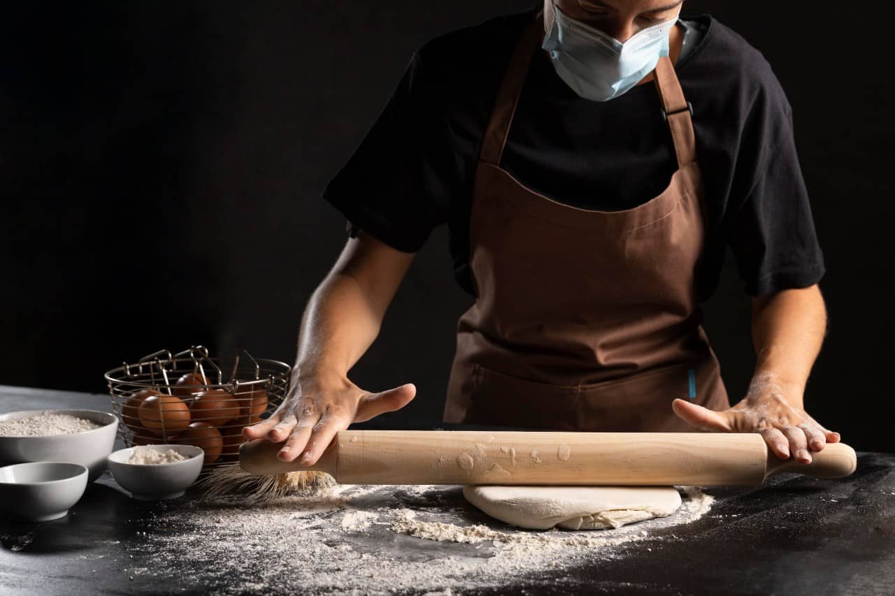 chef with medical mask rolling pin dough