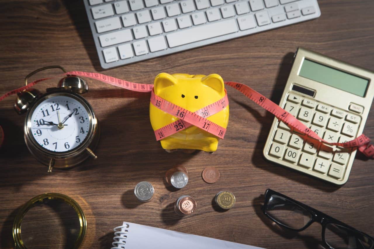 Piggy bank with measuring tape, coins and business objects.