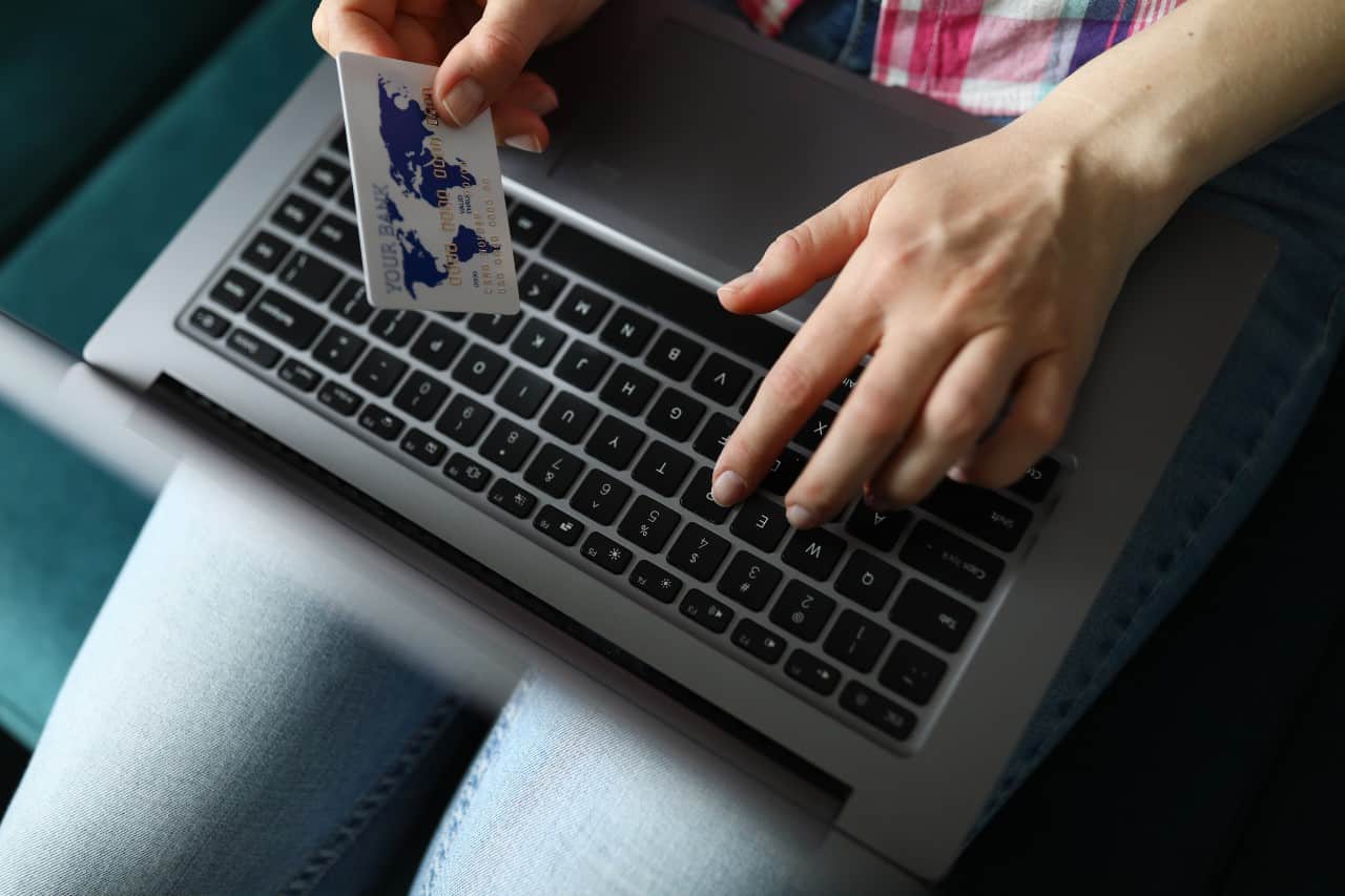 woman holds laptop with card on her hands