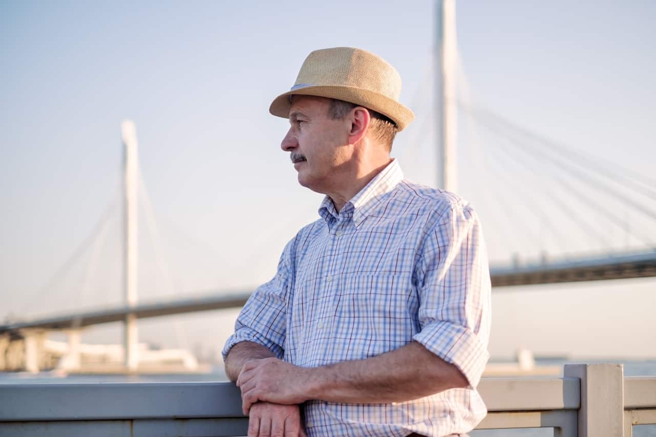 man with hat standing next to sea bridge