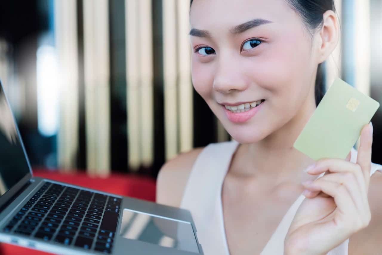 pretty young lady holding credit card and laptop