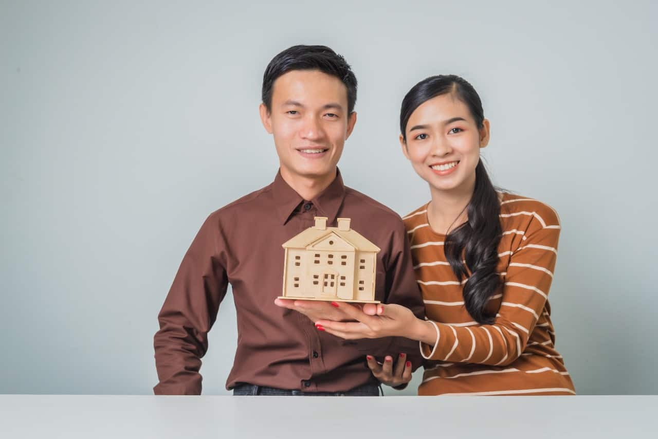 young couple holding figure of house