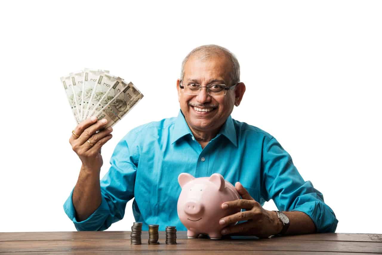 senior indian holding cash happy piggy bank